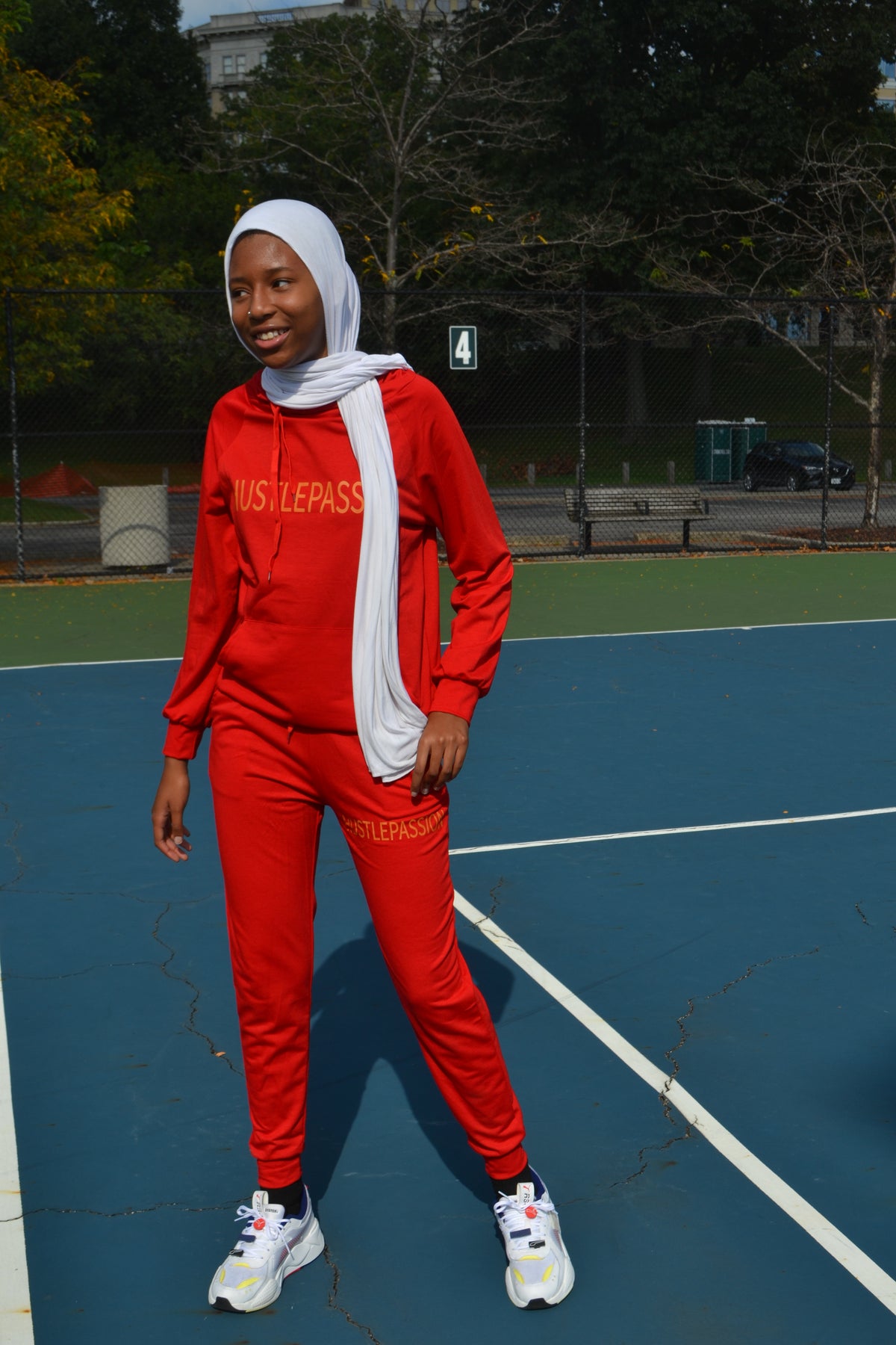 Full-length view of a woman wearing the currant red jogging suit on a tennis court