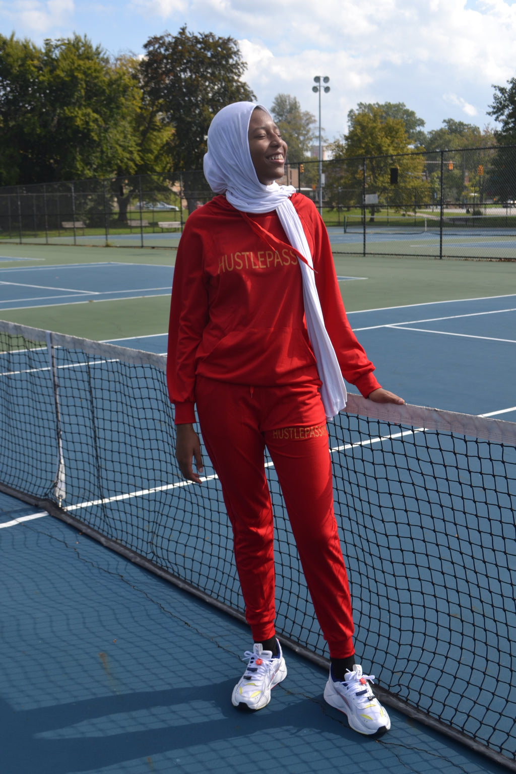 Woman wearing the currant red Hustle Passion jogging suit on a tennis court