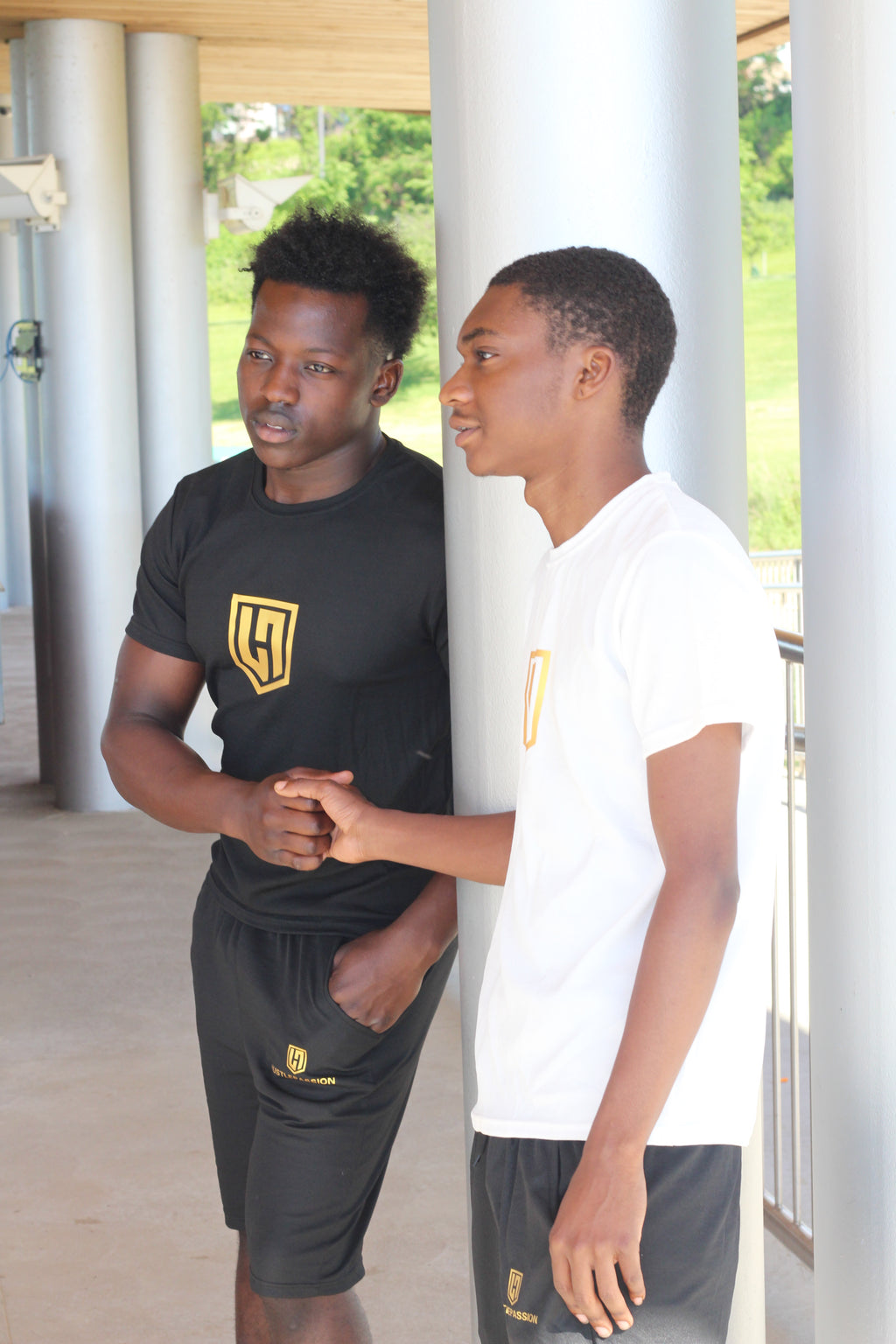 Two models in Hustle Passion T-shirt and shorts sets, one black and one white, shaking hands outdoors