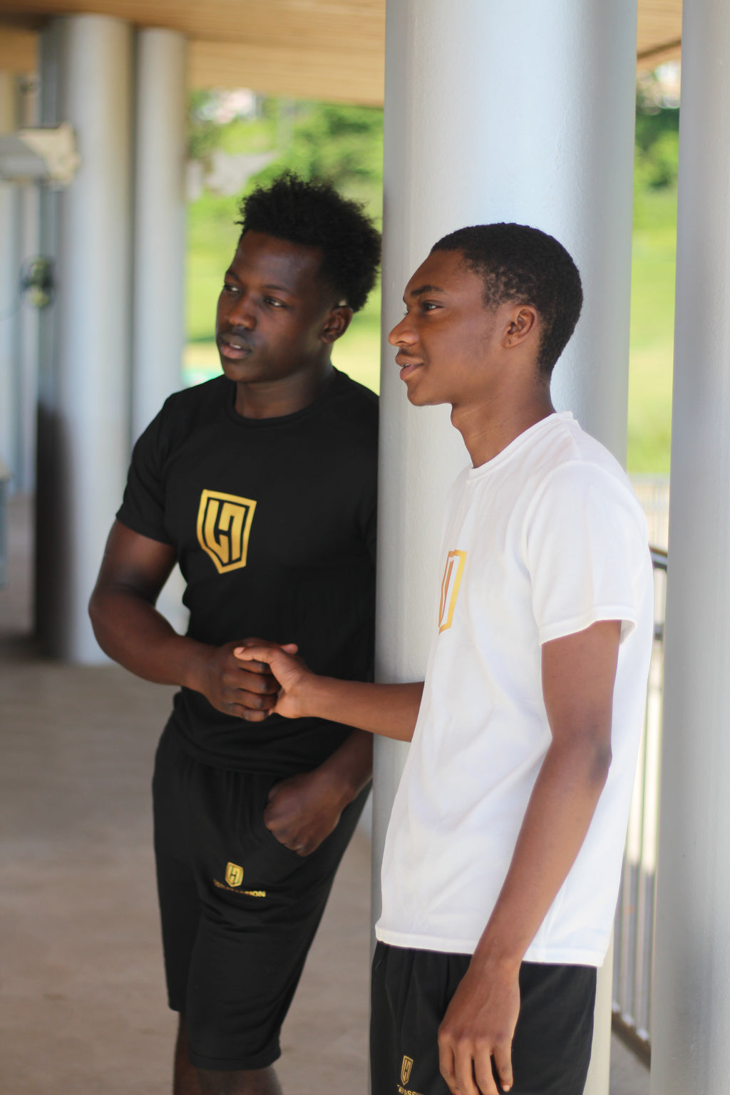 Two models talking outdoors, wearing black and white Hustle Passion T-shirt and shorts sets