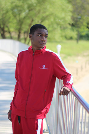 Model wearing the Hustle Passion bloody red tracksuit, leaning on a railing outdoors