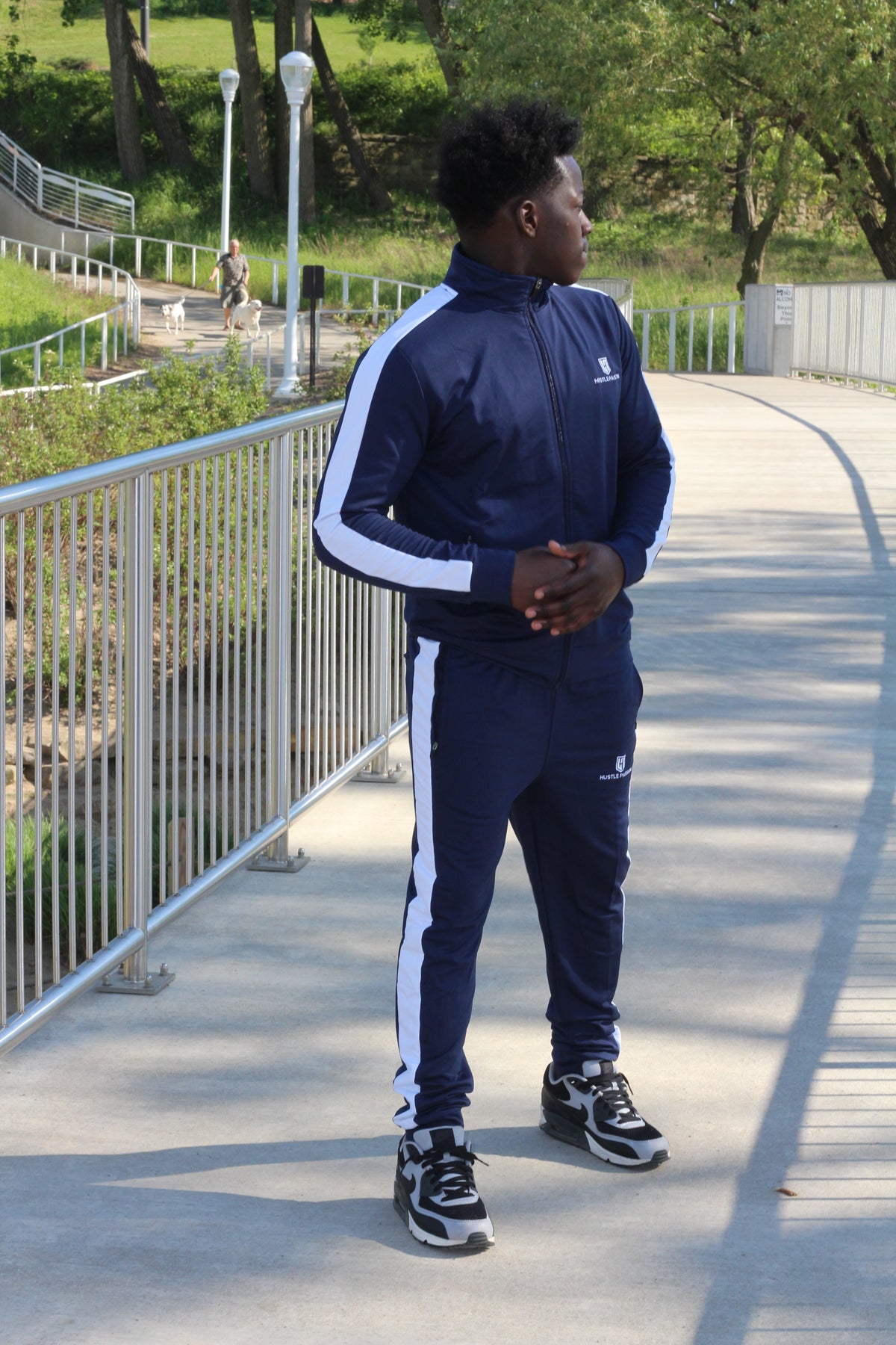 Model standing on a walkway wearing the navy blue tracksuit set