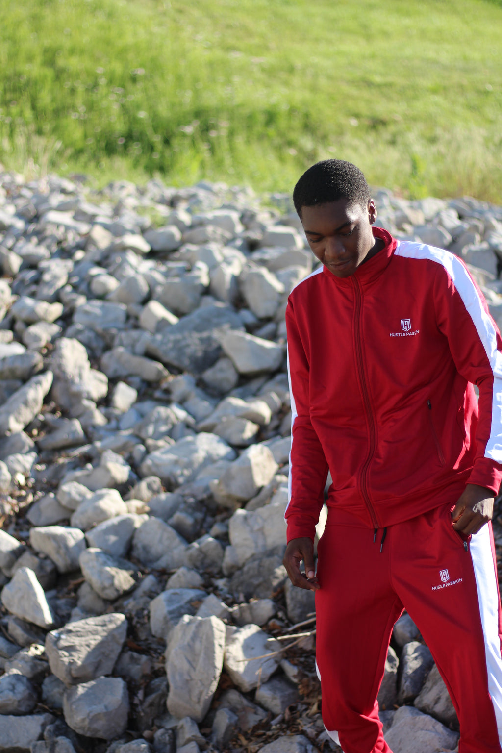 Model in the bloody red tracksuit standing among rocks outdoors