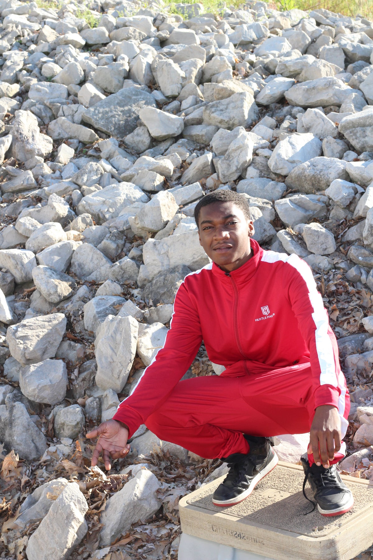 Model crouching on rocks wearing the bloody red tracksuit set